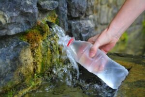 Source of spring water bottle filling holding hand